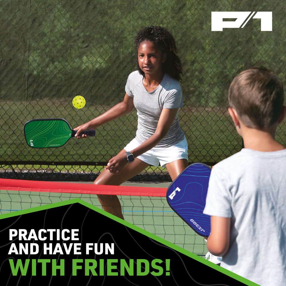 Two children playing pickleball outdoors with green and blue P1 paddles and yellow ball near chain-link fence