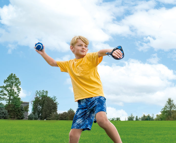 Boy wearing yellow shirt and blue shorts playing Toss & Catch Ball Game outdoors on green grass under partly cloudy sky