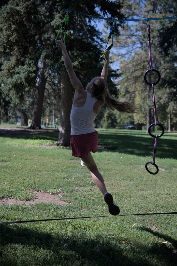 Kids playing on Combo Ninja XL backyard obstacle course with rope line, rings, and cargo net obstacles