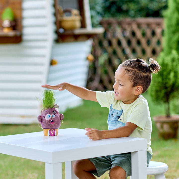 Child interacting with a toy plant pal on a table outdoors